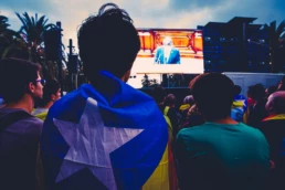 Catalan independence referendum 2017: demonstrator wrapped in the estelada flag watches the big screen