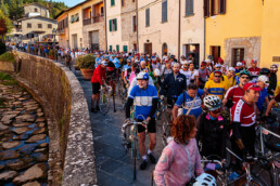 L'Eroica vintage cycling riders passing through the narrow streets of Gaiole in Chianti